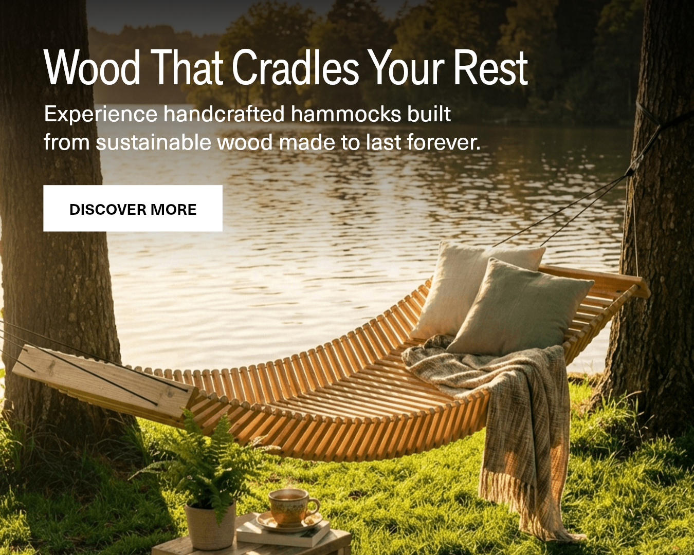 Wooden hammock with pillows and a blanket in a natural setting by a lake.